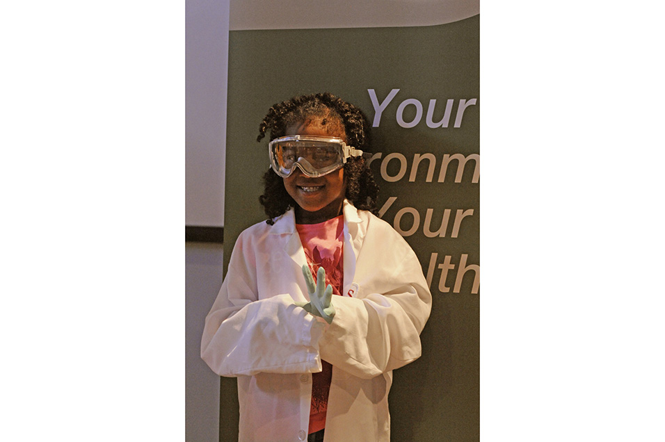 One particpant wearing a lab coat, goggles, and gloves