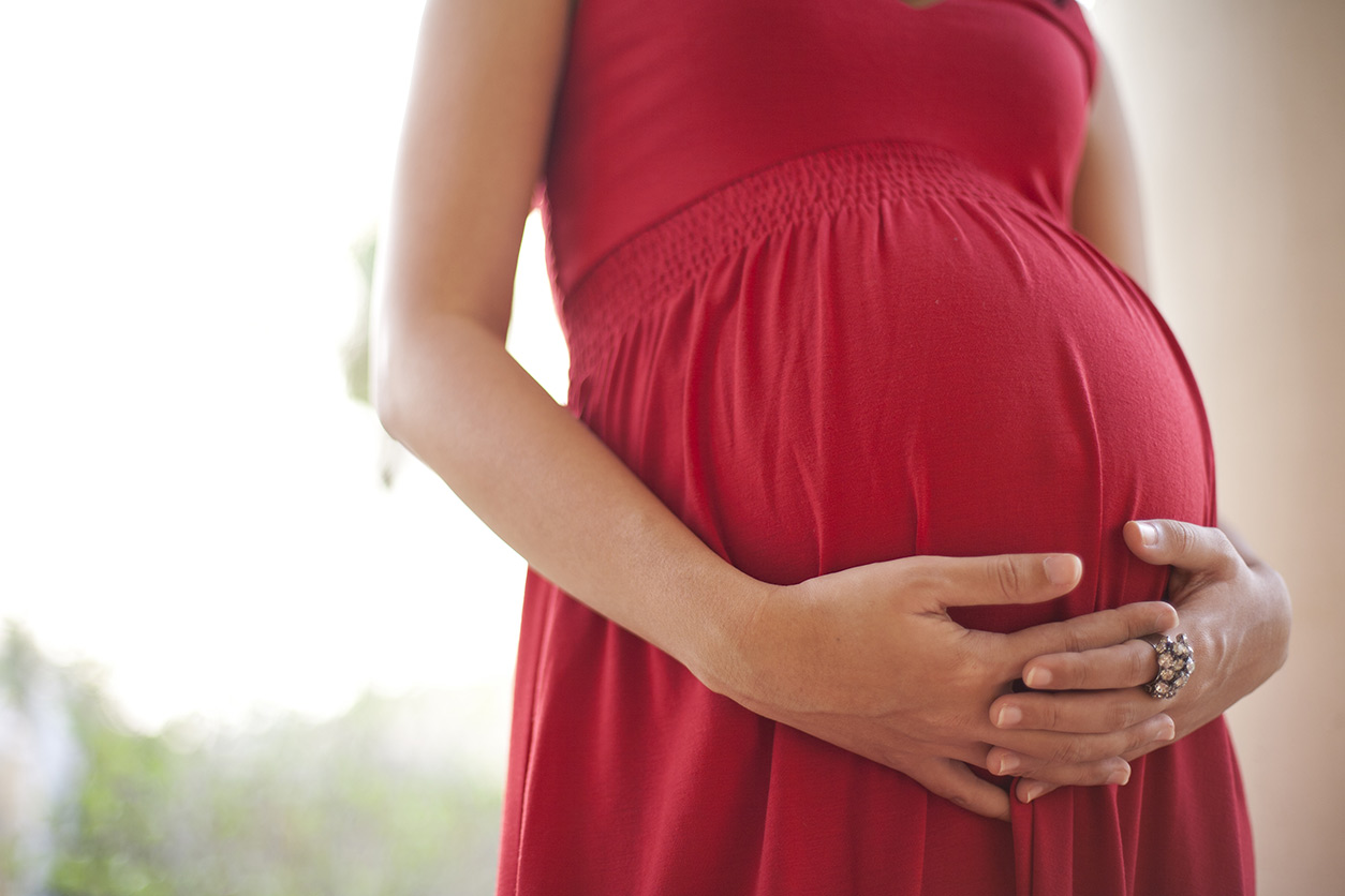pregnant woman in red dress holding belly