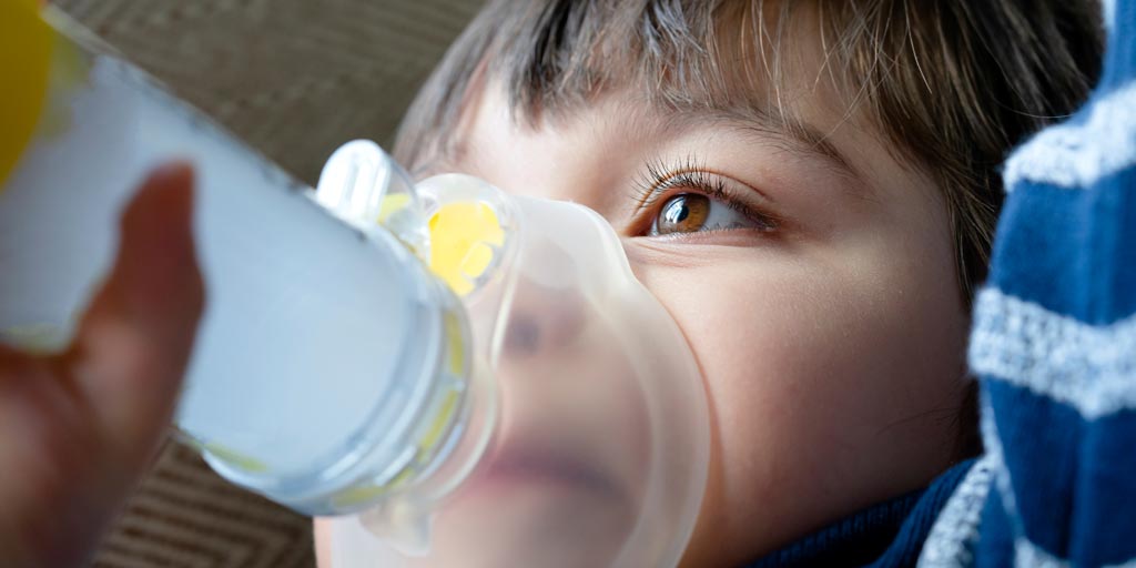 boy uses asthma inhaler