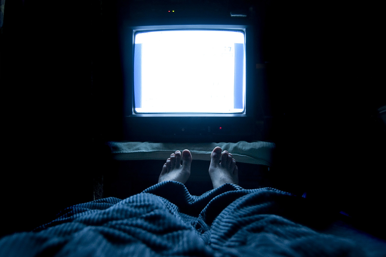 feet under cover with television in the background