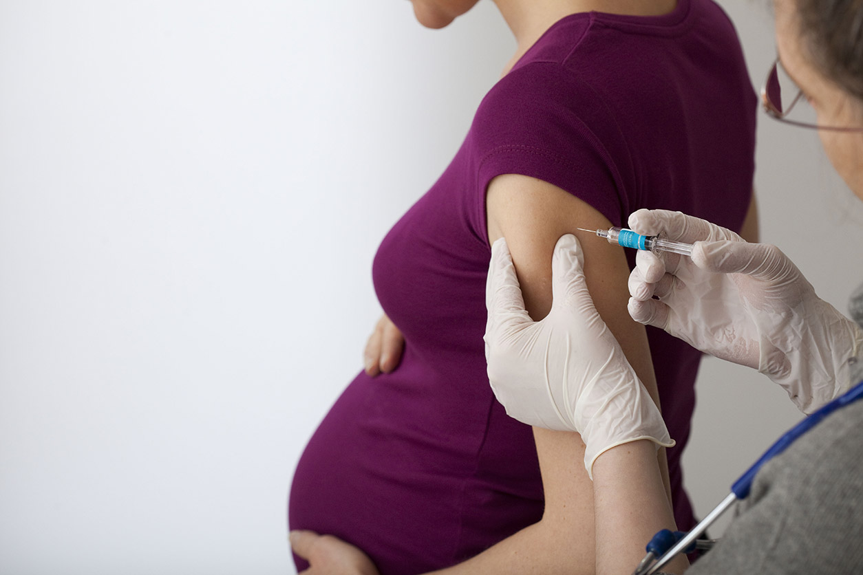 Pregnant woman getting a vaccination shot in the arm