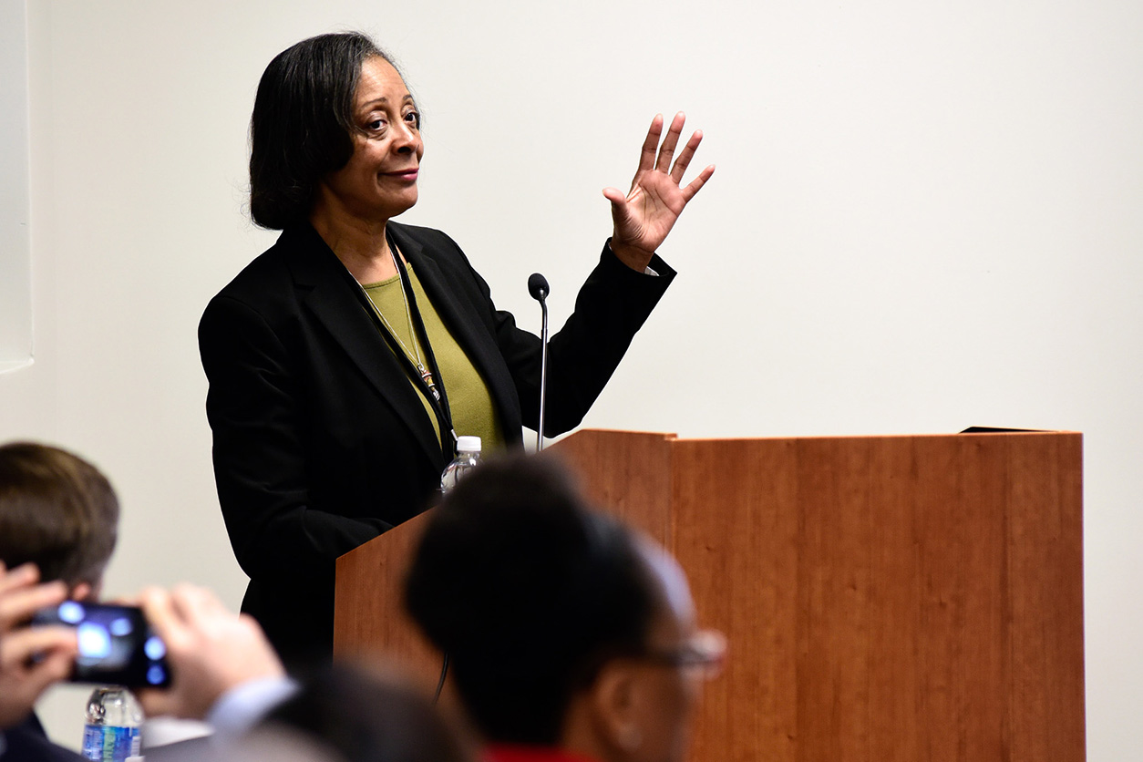 Darlene Dixon, D.V.M., Ph.D. raises left hand while at podium