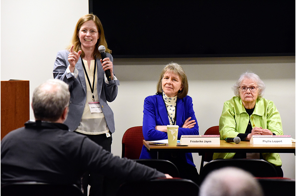Quaker Harmon, M.D., Ph.D. holds microphone and Friederike Jayes, D.V.M., Ph.D., Phyllis Leppert, M.D. and Donna Baird, Ph.D. seated at table
