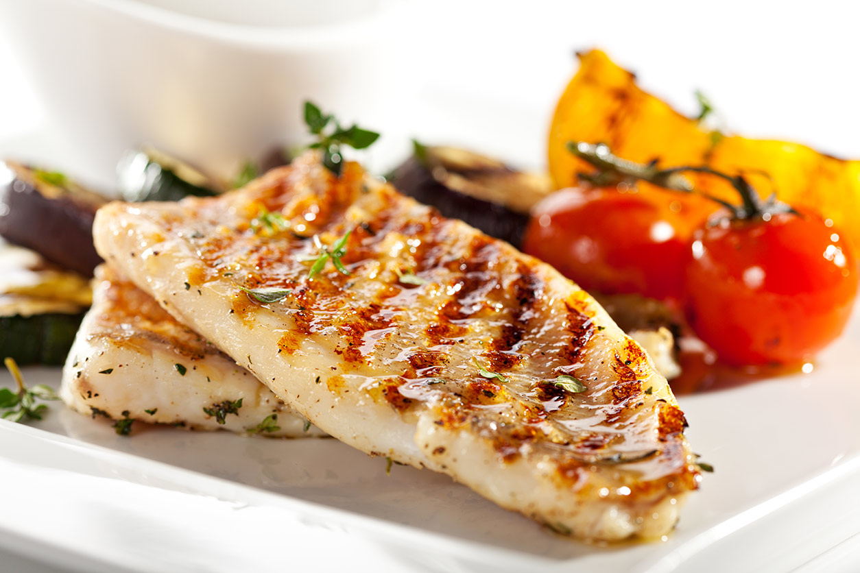 grilled fish fillet with vegetables in the background