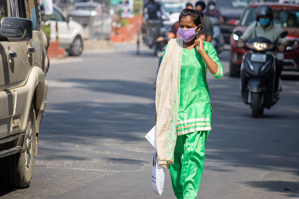 a woman walking on a road wearing a face mask