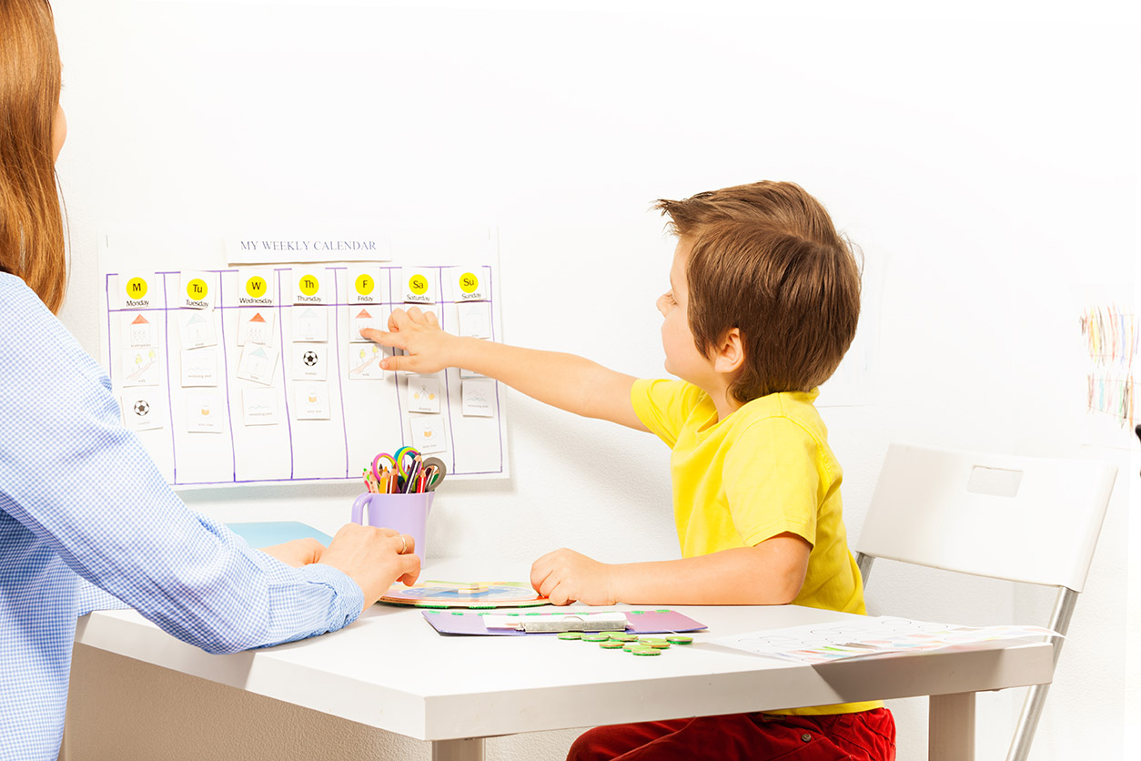 boy points at days and activities calendar