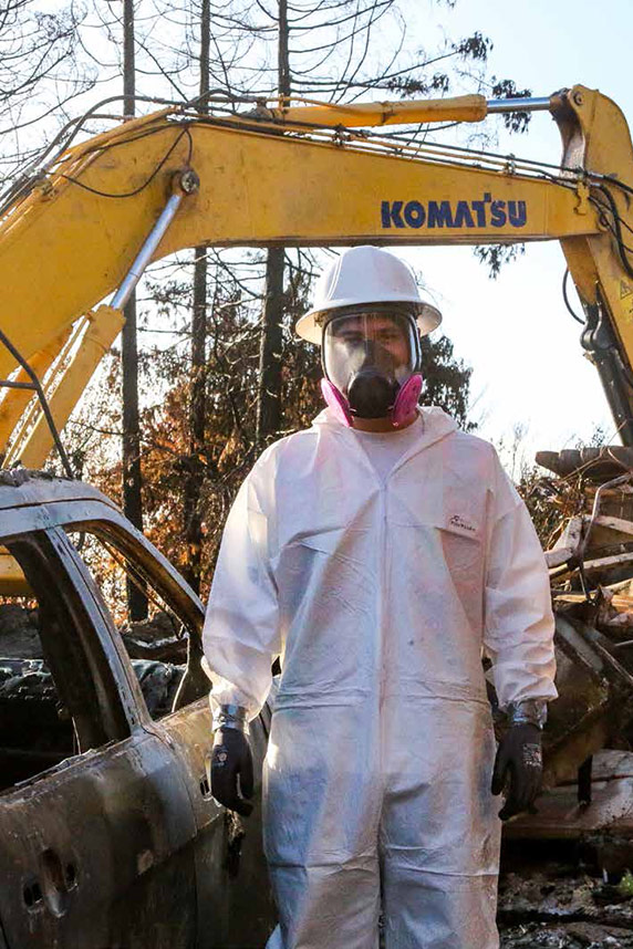 Wildfire cleanup worker wearing full protective suit