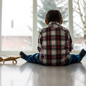 Boy sitting on floor with toy airplane next to him