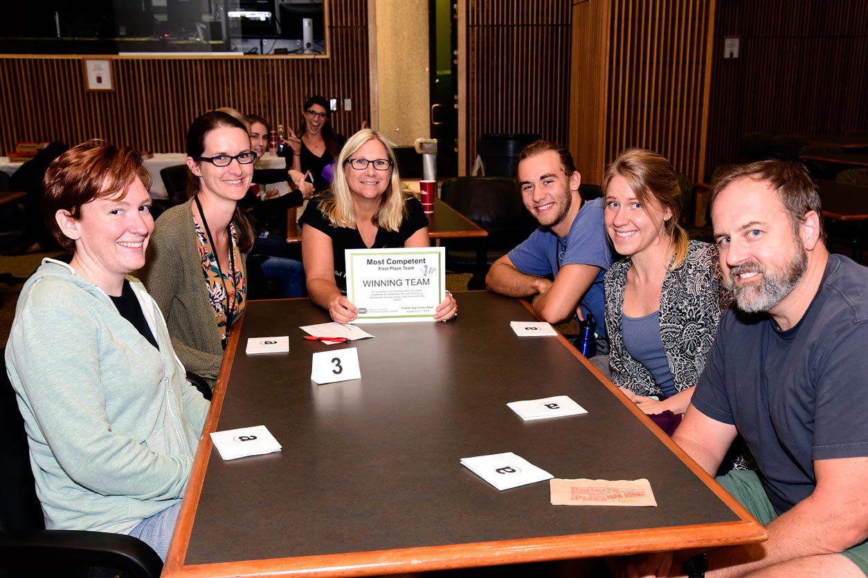 Fellows sit around a table with the award won for a trivia challenge