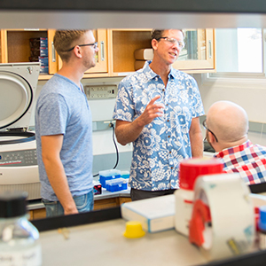three men speaking in a lab