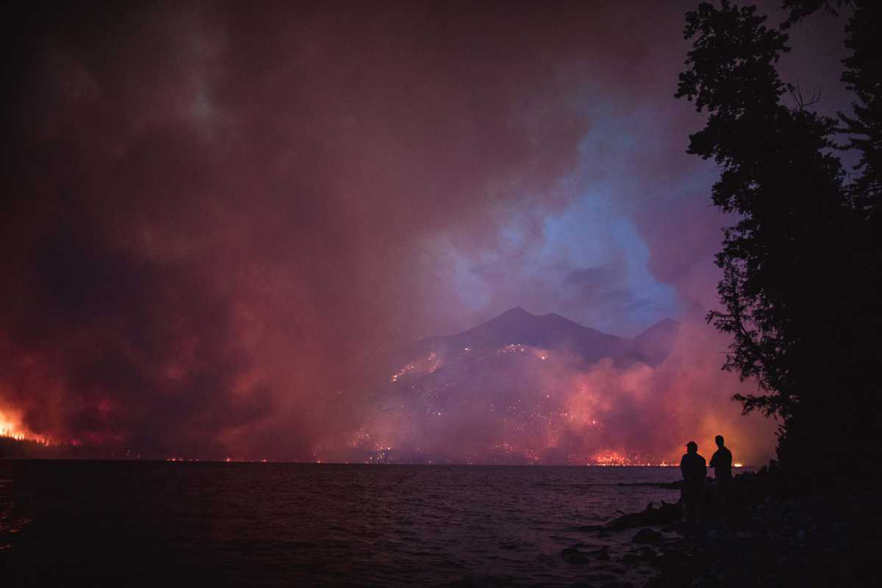 wildfire burns mountains overlooking lake