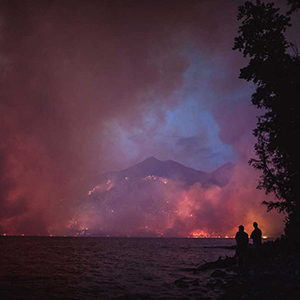 wildfire burning mountains overlooking lake