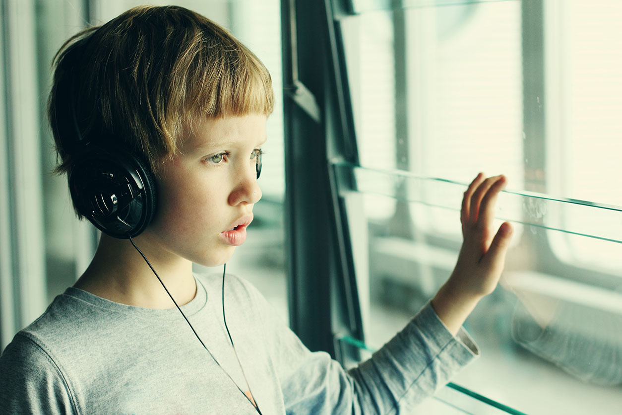 boy wearing headphones looking out a window