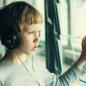 Boy looking out window with headphones over ears