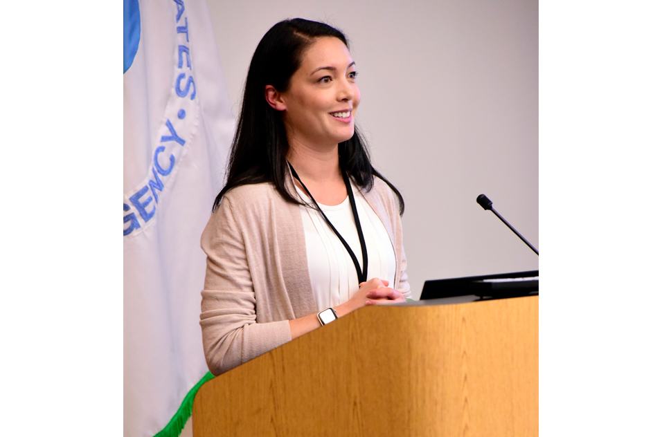 Alisa Suen Wallach, Ph.D. stands at podium