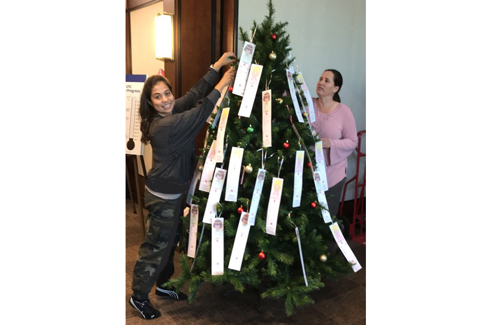 Esra Mutlu, Ph.D. and Vicki Sutherland, Ph.D. hang angel tags on a tree