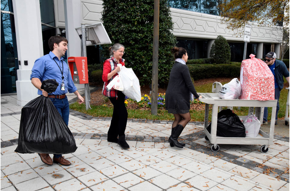 several volunteers carrying bags of gifts