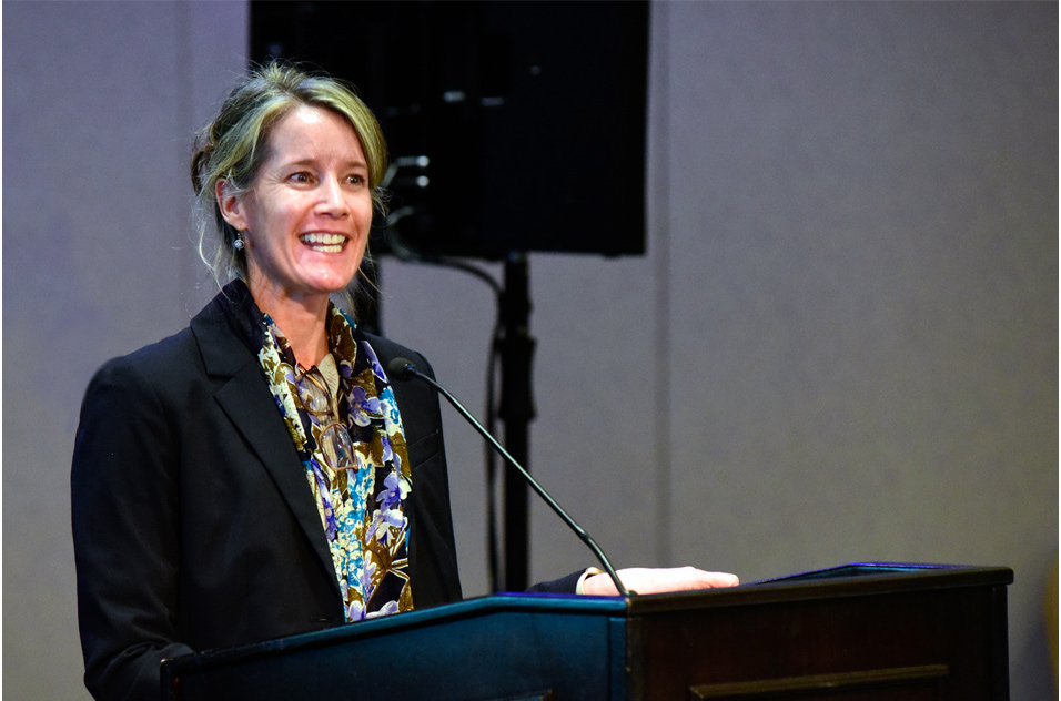 Michelle Heacock, Ph.D. smiles from the podium