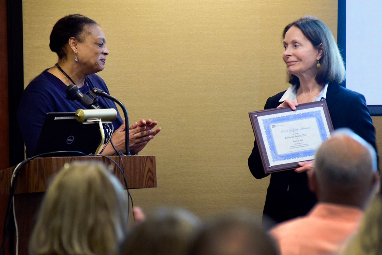 Angela King-Herbert, D.V.M. stands by Frederica Perera, Ph.D. holding an award