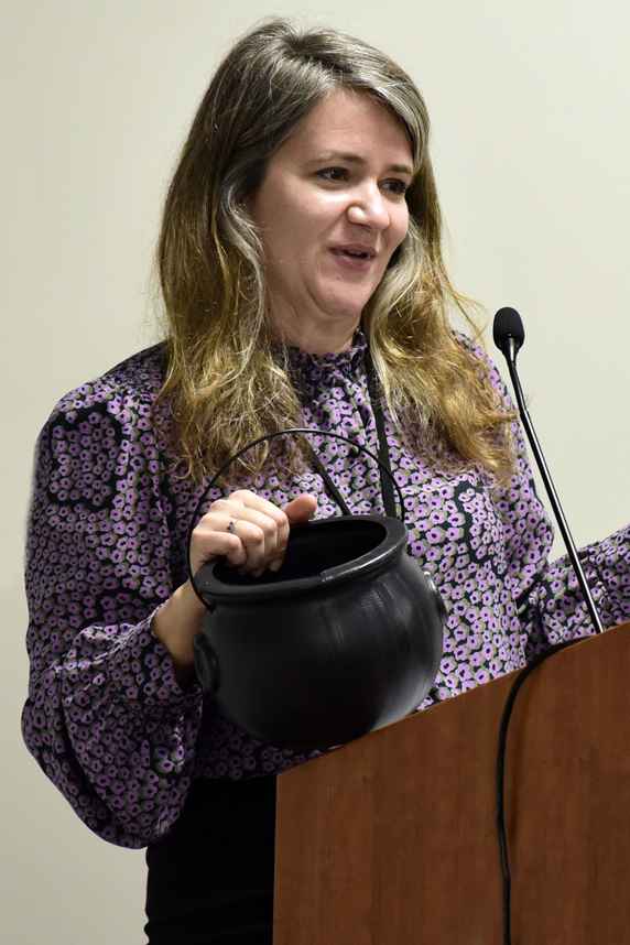 Tammy Collins, Ph.D. holds a black bowl while standing at the podium