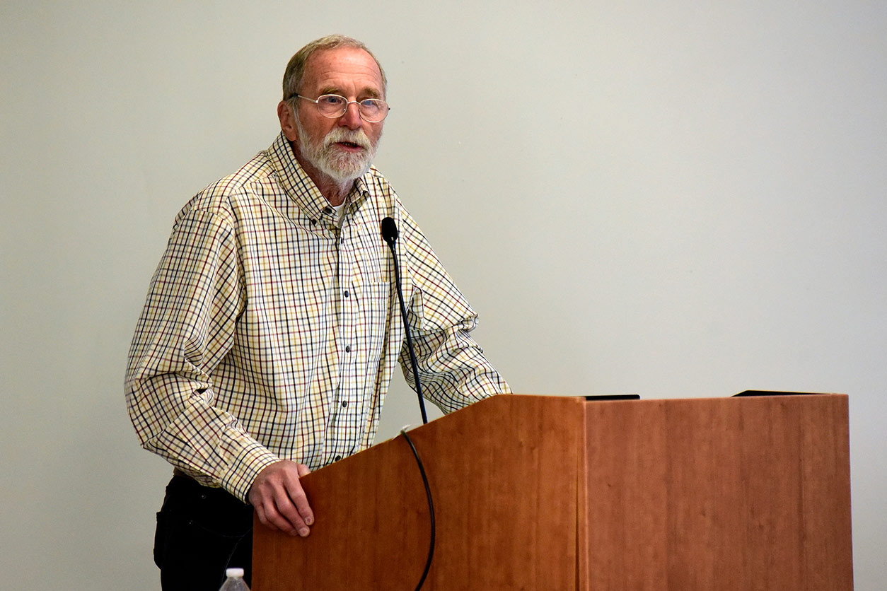 John Cidlowski, Ph.D. stands at podium