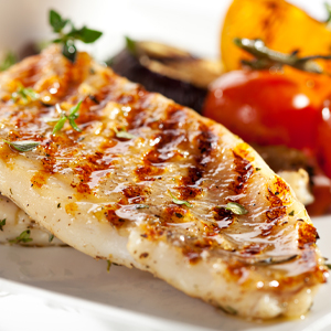 grilled fish fillet with vegetables in the background