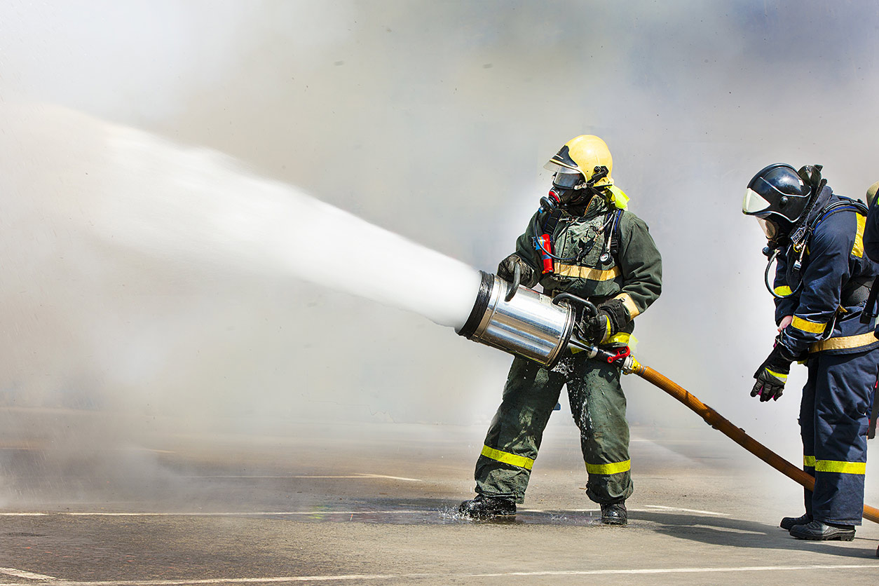 Firemen extinguish a fire with foam within the smoke
