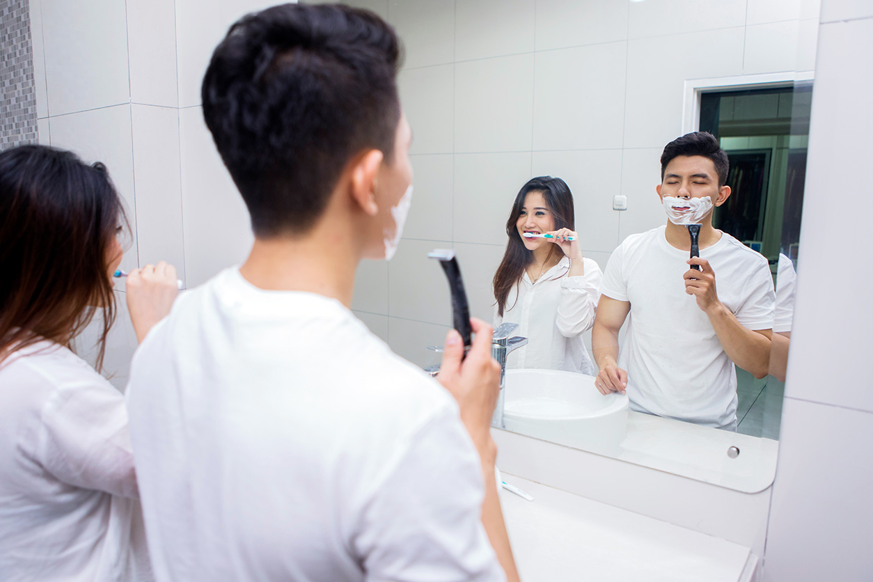 two people in a mirror, shaving and brushing teeth