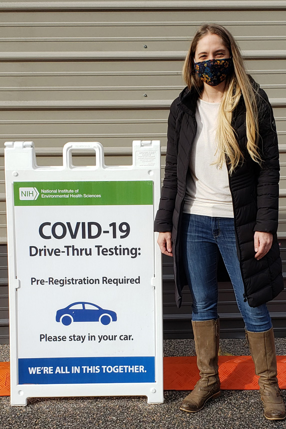 Kristen Ryan stands with COVID-19 Testing Drive-Thru sign