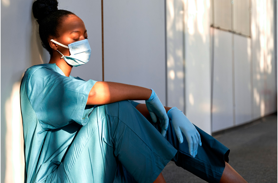 health care worker rests against a wall