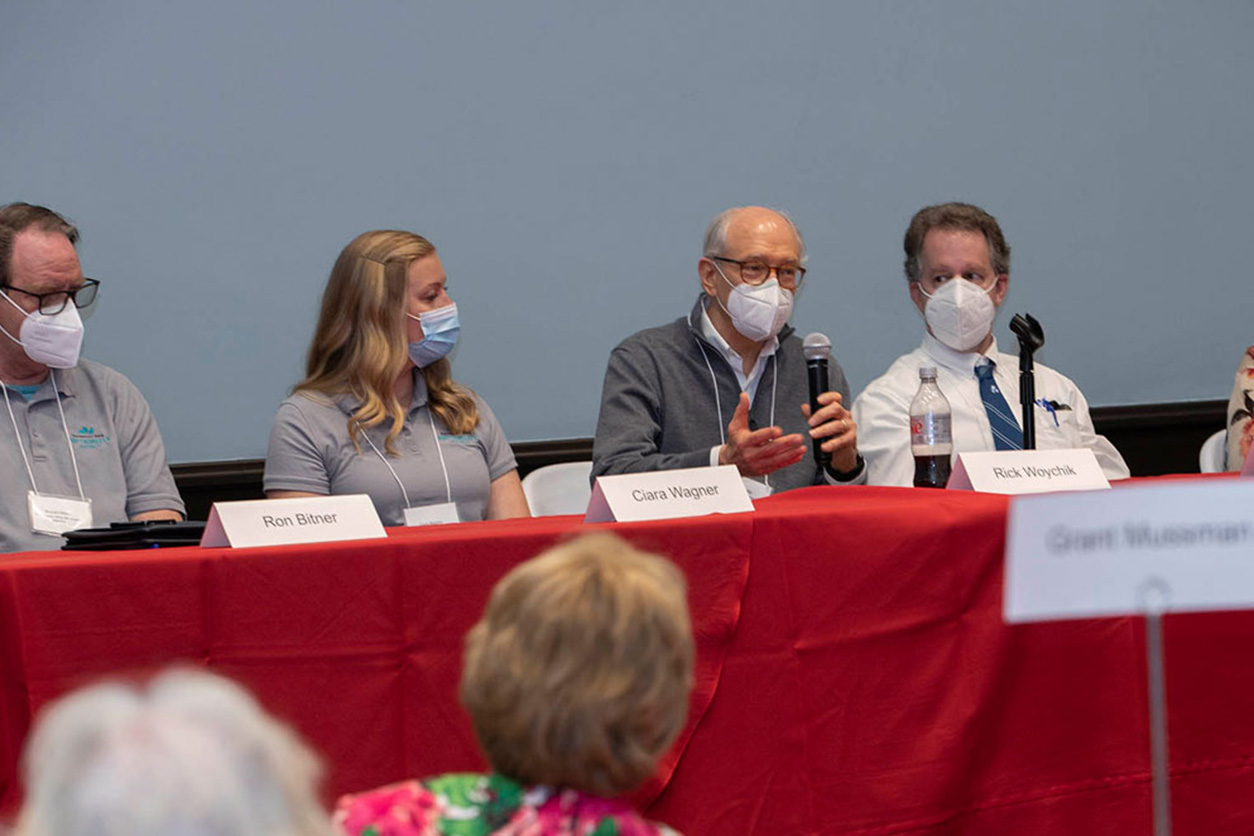 Masked panelists speaking during a forum