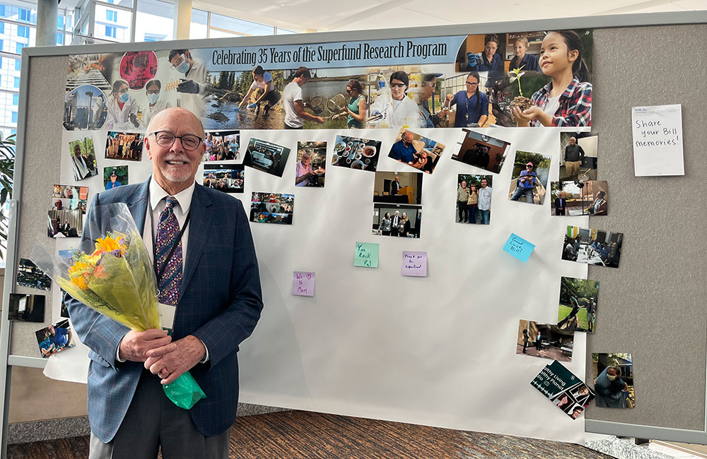William Suk, Ph.D., stands in front of memory wall with added photos and well wishes.