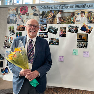 William Suk, Ph.D., stands in front of memory wall with added photos and well wishes.