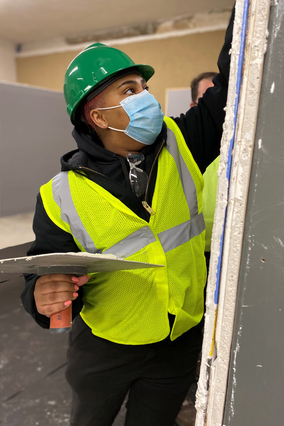 Crisalida Chaplin, a Building Pathways trainee, applies drywall