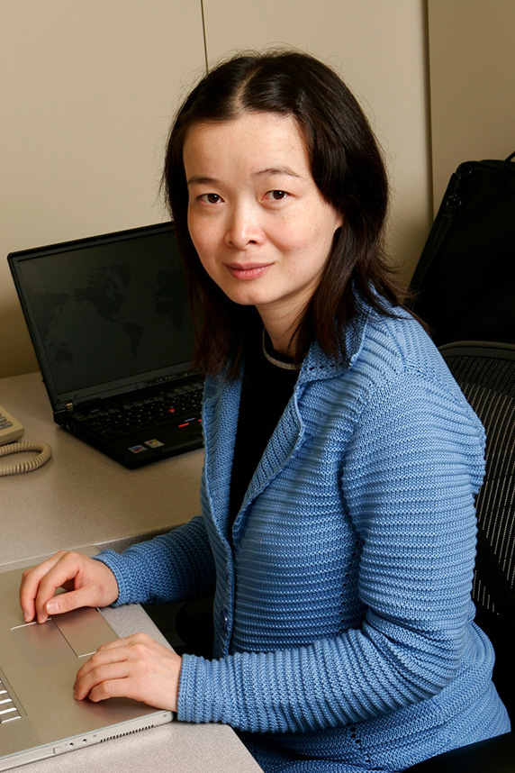 Xiaoling Li poses while sitting at her desk