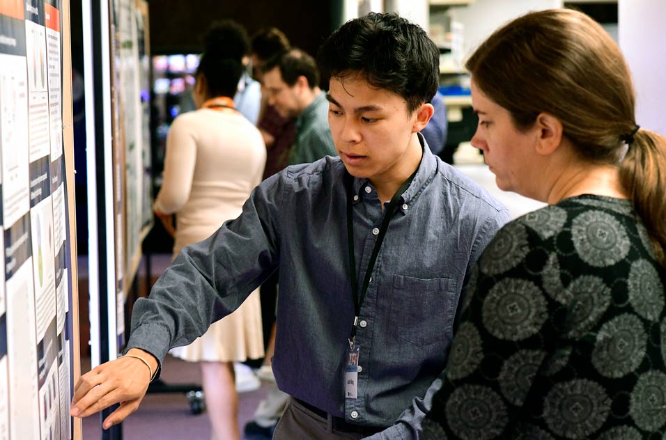 First place Undergraduate Poster awardee, Justin Wang, describes his findings to judge Amy Papaneri, a biologist in the In Vivo Neurobiology Group. 