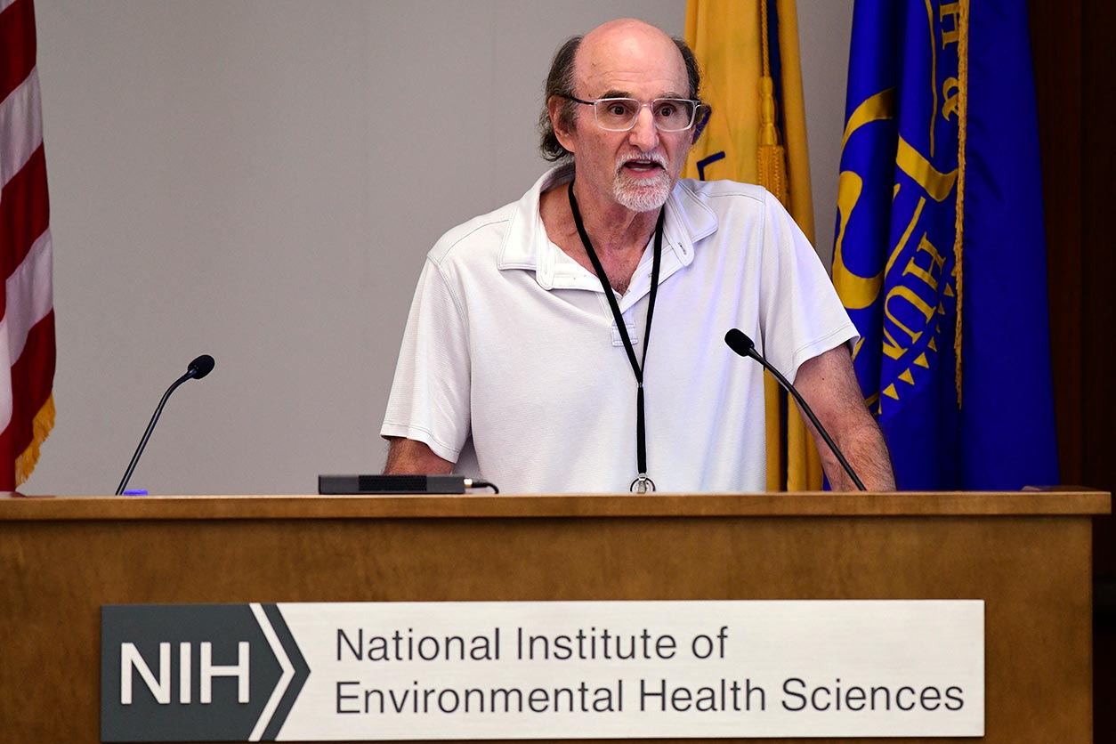 Bill Copeland, Ph.D., stands behind podium and microphones