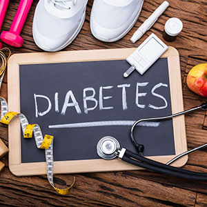 chalk board saying diabetes with shoes, work out equipment and apple around it