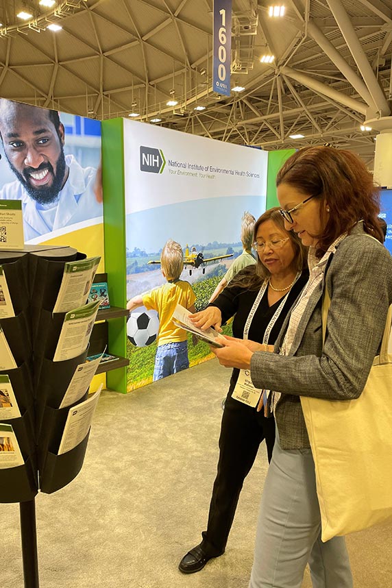 Virginia Matthews, left, of the NIEHS Office of Communications and Public Liaison (OCPL) explains institute programs to APHA attendees who stopped at the NIEHS exhibit booth.