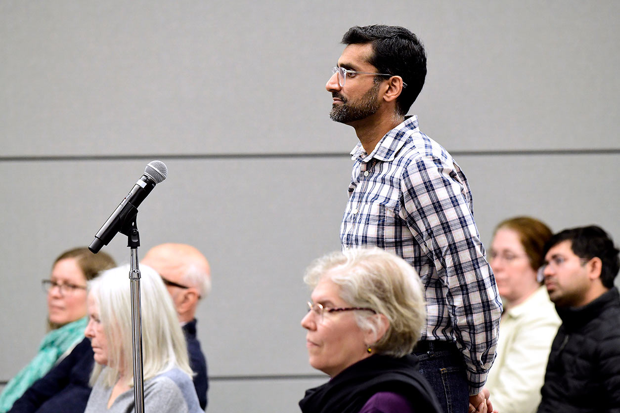 Man stands at microphone while audience listens 