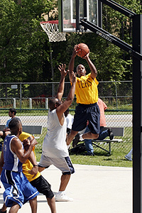 A group of men playing basketball. One player is shooting the ball.