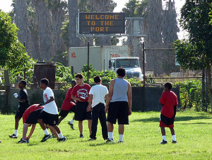 Young men play soccer beneath a sign that reads 'Welcome to the Port'